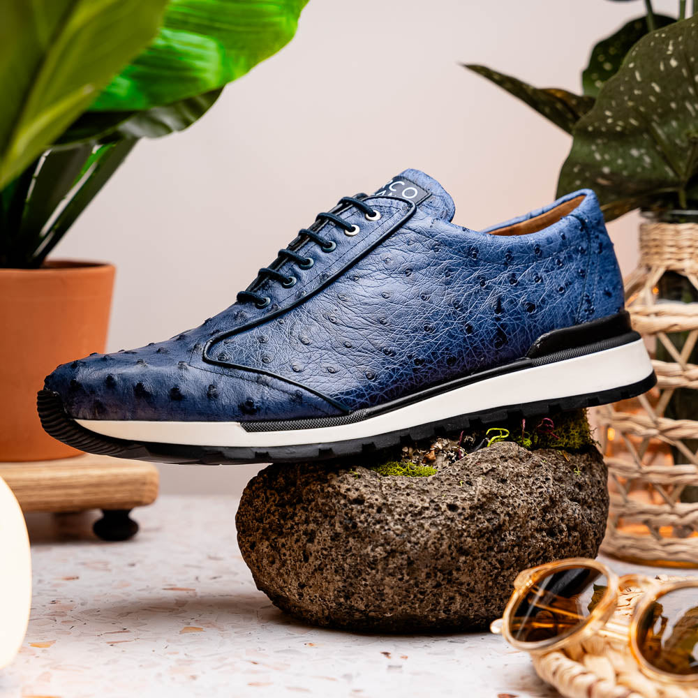 The Marco Di Milano Scanno Antique Navy sneaker features genuine ostrich quill leather in blue, black laces, a white and black rubber sole, and textured details—luxury footwear displayed on a white background.