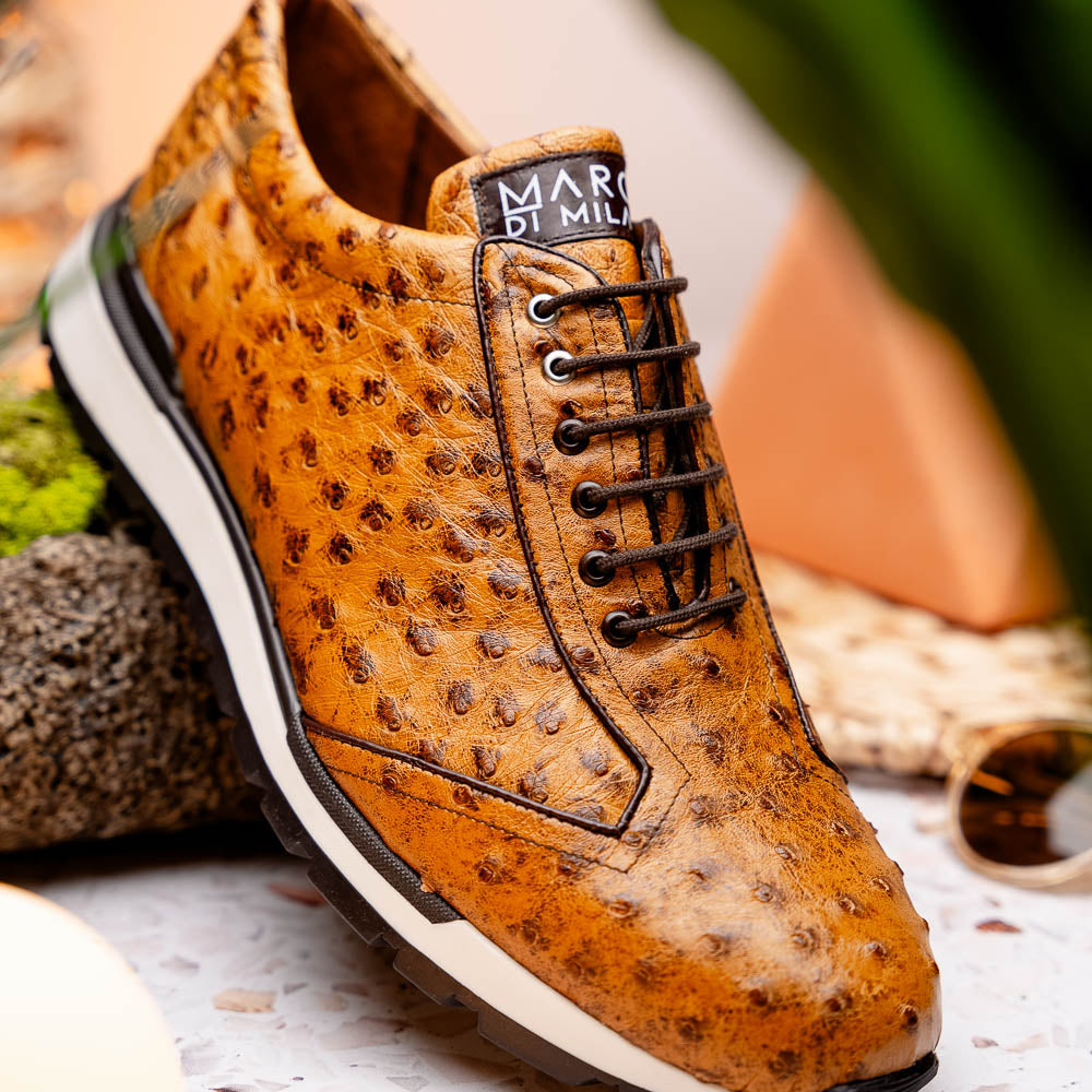 The Scanno Antique Paja sneakers by Marco Di Milano feature real ostrich quill leather with a hand-painted finish, brown leather, black laces, and white-accented soles—one shoe propped on the other against a white background.