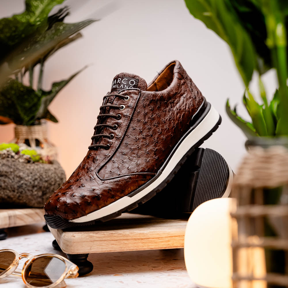 The Scanno Antique Brown sneaker by Marco Di Milano features genuine ostrich quill leather in brown, black laces, and a white-and-black rubber sole. One shoe stands upright while the other rests on its side, highlighting the hand-painted finish.