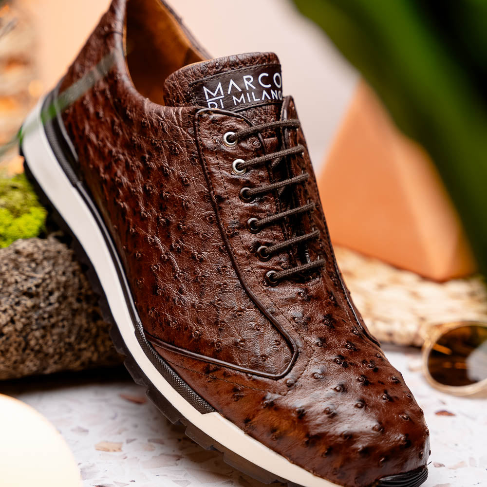 The Scanno Antique Brown sneaker by Marco Di Milano features genuine ostrich quill leather in brown, black laces, and a white-and-black rubber sole. One shoe stands upright while the other rests on its side, highlighting the hand-painted finish.