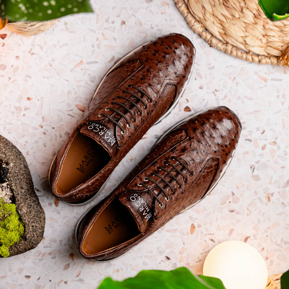 The Scanno Antique Brown sneaker by Marco Di Milano features genuine ostrich quill leather in brown, black laces, and a white-and-black rubber sole. One shoe stands upright while the other rests on its side, highlighting the hand-painted finish.