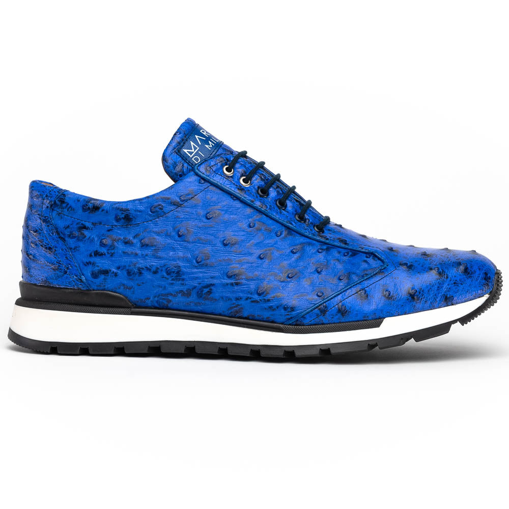 The Scanno Electric Blue sneakers by Marco Di Milano feature textured blue leather, black laces, white soles, and a hand-painted finish—luxury footwear shown upright and leaning to display the black tread.
