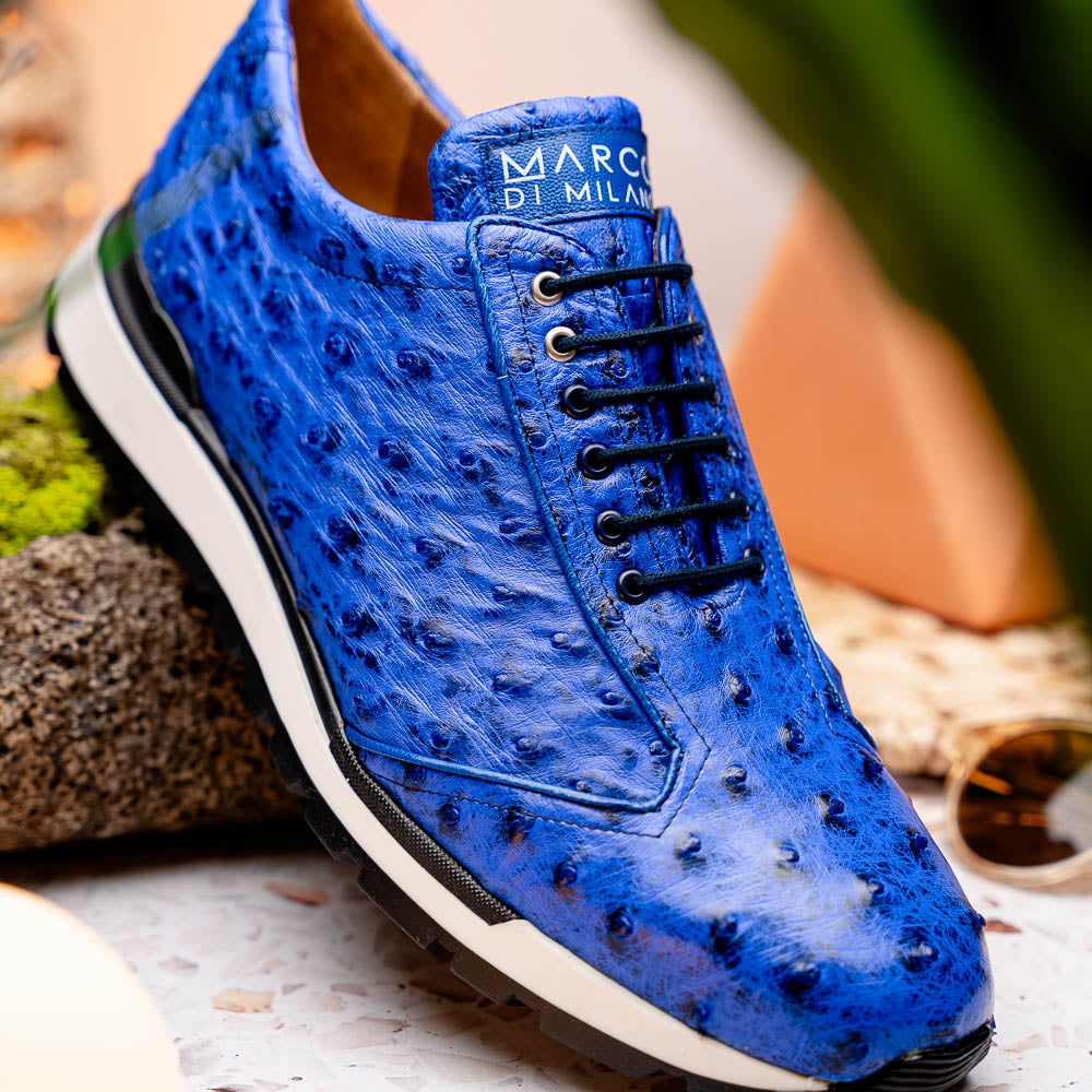 The Scanno Electric Blue sneakers by Marco Di Milano feature textured blue leather, black laces, white soles, and a hand-painted finish—luxury footwear shown upright and leaning to display the black tread.