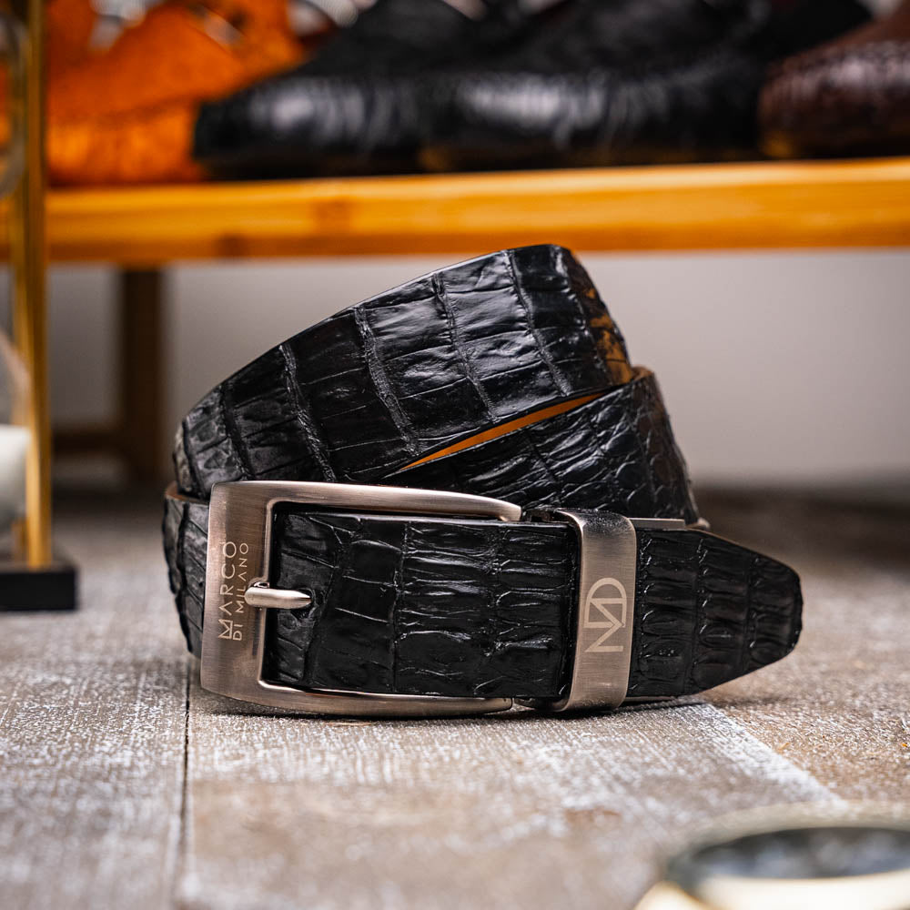 Silvio Belt Black by Marco Di Milano—crafted from black crocodile-embossed leather in the refined style of caiman fuscus-back belts, this belt features meticulous hand-painted finishes and a silver buckle engraved with the Marco Di Milano logo, elegantly coiled on a white background.