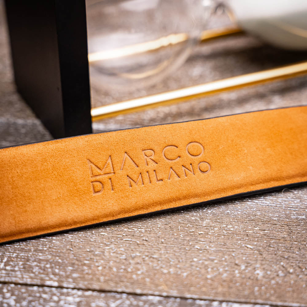 Silvio Belt Black by Marco Di Milano—crafted from black crocodile-embossed leather in the refined style of caiman fuscus-back belts, this belt features meticulous hand-painted finishes and a silver buckle engraved with the Marco Di Milano logo, elegantly coiled on a white background.