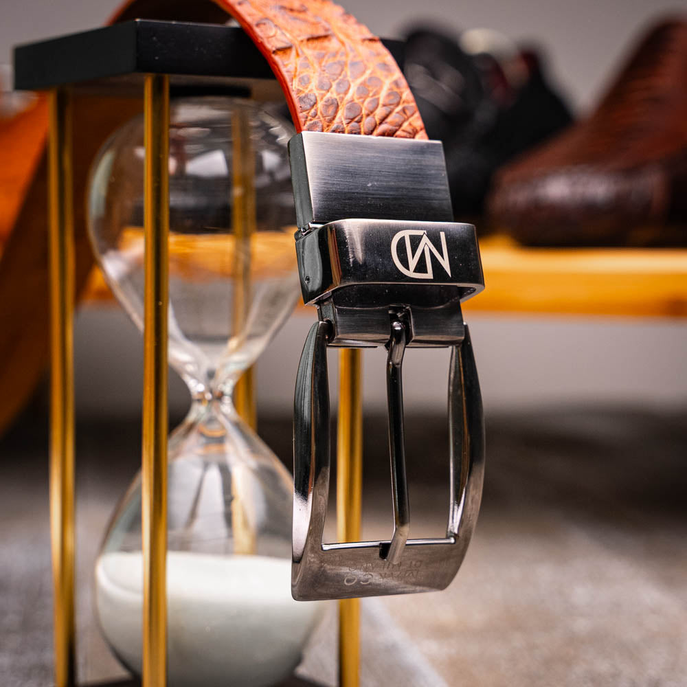Silvio Belt Rustic Cognac by Marco Di Milano: a brown crocodile-pattern leather belt inspired by caiman fuscus-back, featuring a silver buckle engraved with "MARCO" and "MD"—a signature luxury accessory.