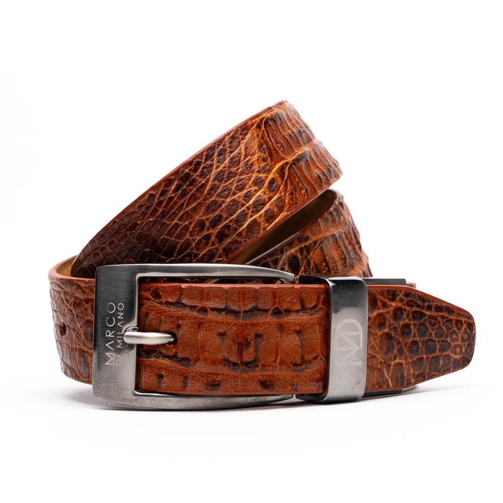 Silvio Belt Rustic Cognac by Marco Di Milano: a brown crocodile-pattern leather belt inspired by caiman fuscus-back, featuring a silver buckle engraved with "MARCO" and "MD"—a signature luxury accessory.