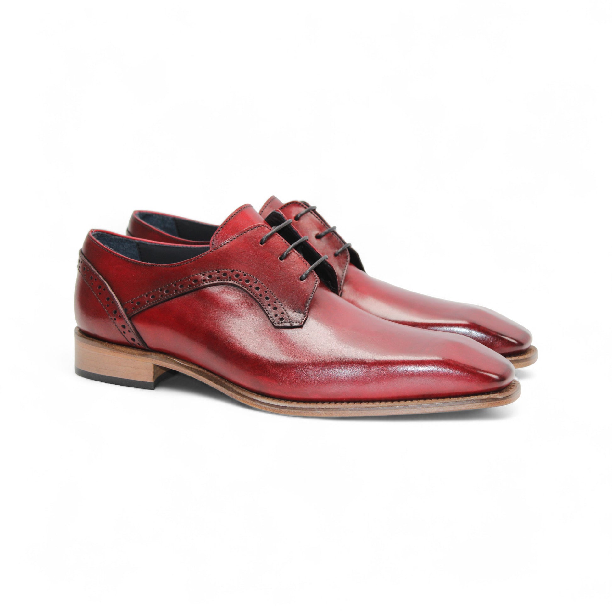 The Duca Di Matiste Duca Spada Antique Red is an Italian leather dress shoe in red with brogue detailing, black laces, and a light brown wooden sole, shown in profile on a white background.