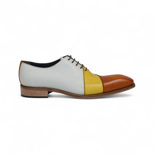 The Duca Spoleto II Yellow Combo by Duca Di Matiste is a luxury leather dress shoe in white, yellow, and brown color blocks with black laces and a light brown sole, expertly handcrafted in Italy and shown in side view on a white background.