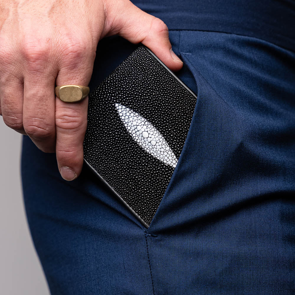 The Marco Di Milano Vallo Wallet Black is a textured luxury men's wallet with a central oval reflective accent, shown partially open on a white background.