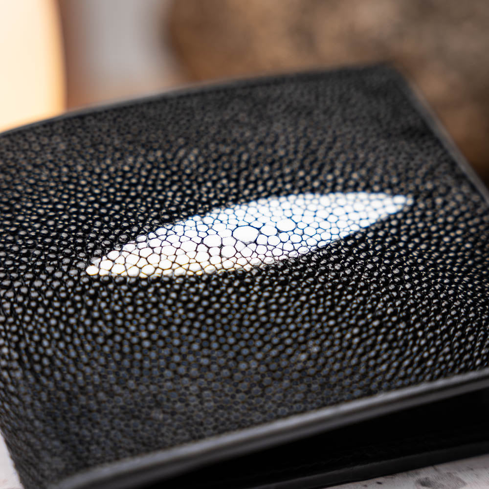 The Marco Di Milano Vallo Wallet Black is a textured luxury men's wallet with a central oval reflective accent, shown partially open on a white background.