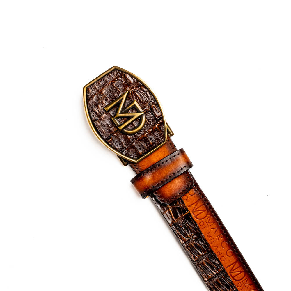 The Texas Belt Aged Maple by Marco Di Milano is crafted from luxurious caiman crocodile skin in a brown finish, featuring a large brass buckle engraved with "MD" and the brand name embossed on the leather.