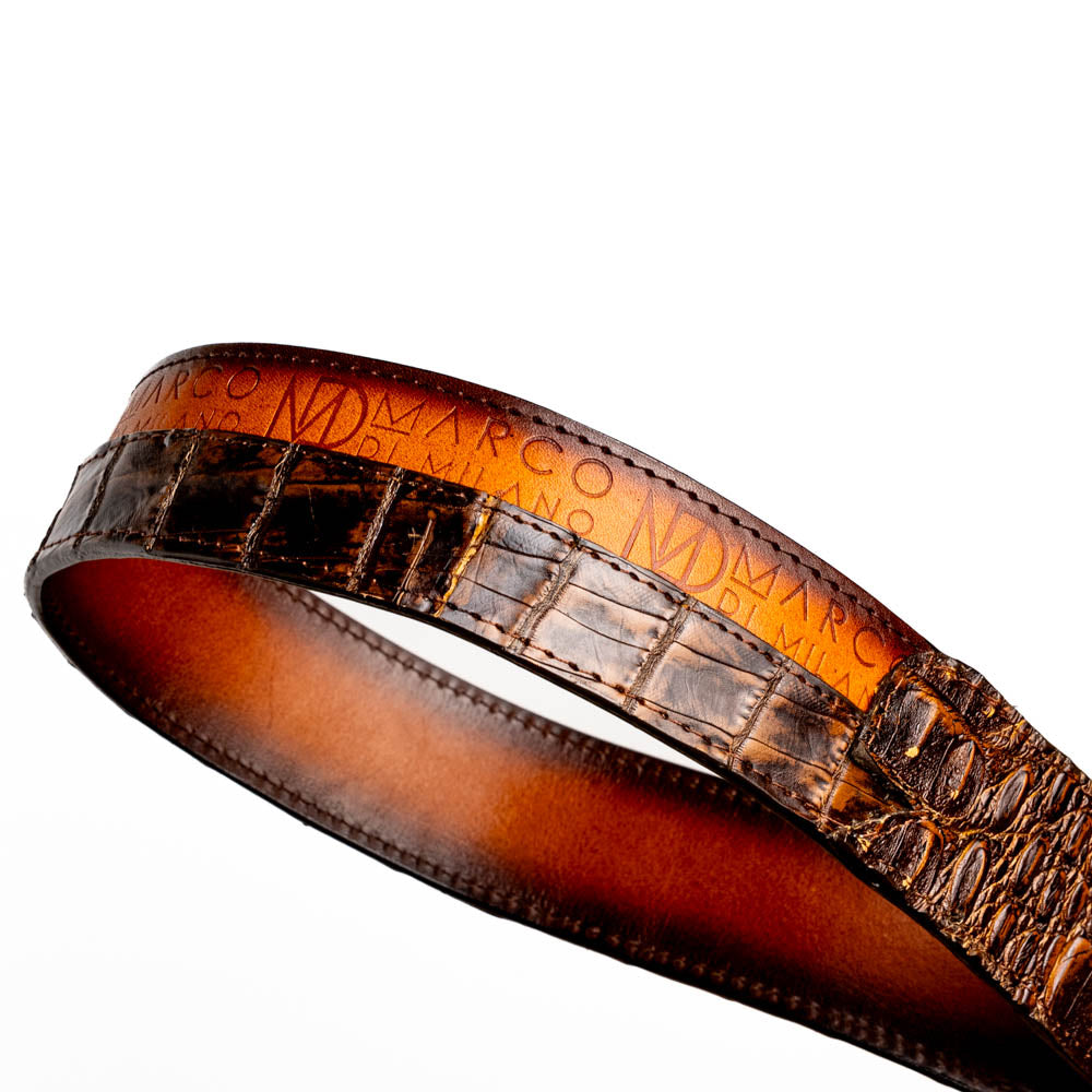 The Texas Belt Aged Maple by Marco Di Milano is crafted from luxurious caiman crocodile skin in a brown finish, featuring a large brass buckle engraved with "MD" and the brand name embossed on the leather.