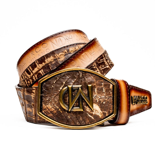 The Texas Belt Stone Brown by Marco Di Milano features embossed brown leather and a large gold-and-brown "CW" buckle, styled after a classic western calfskin belt with "MARCO DI MILANO" branding on the strap.