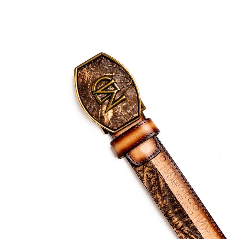 The Texas Belt Stone Brown by Marco Di Milano features embossed brown leather and a large gold-and-brown "CW" buckle, styled after a classic western calfskin belt with "MARCO DI MILANO" branding on the strap.
