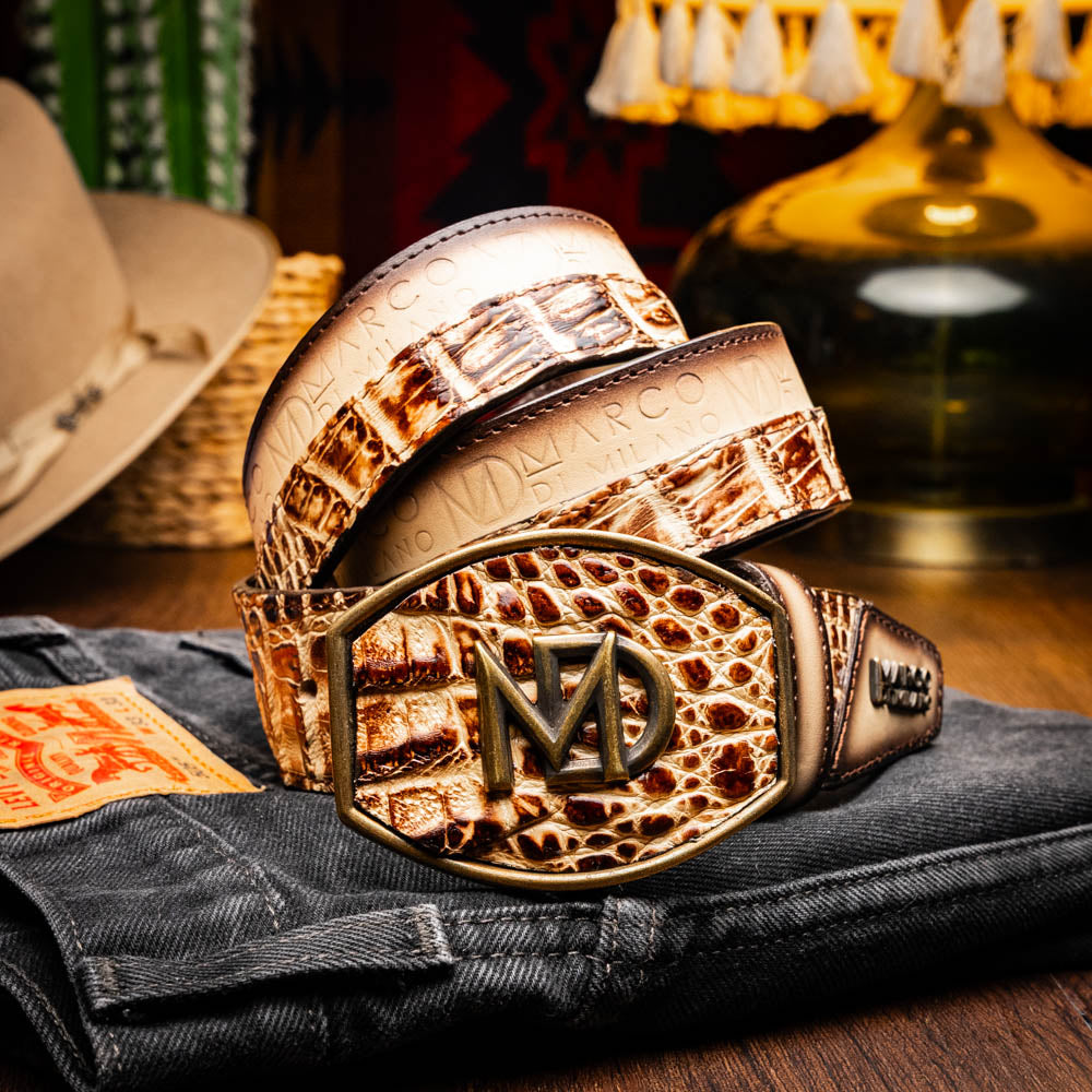 The Texas Belt Stone Orix by Marco Di Milano features embossed tan and brown caiman crocodile leather with a large gold and brown MD logo buckle, shown rolled up against a white background.