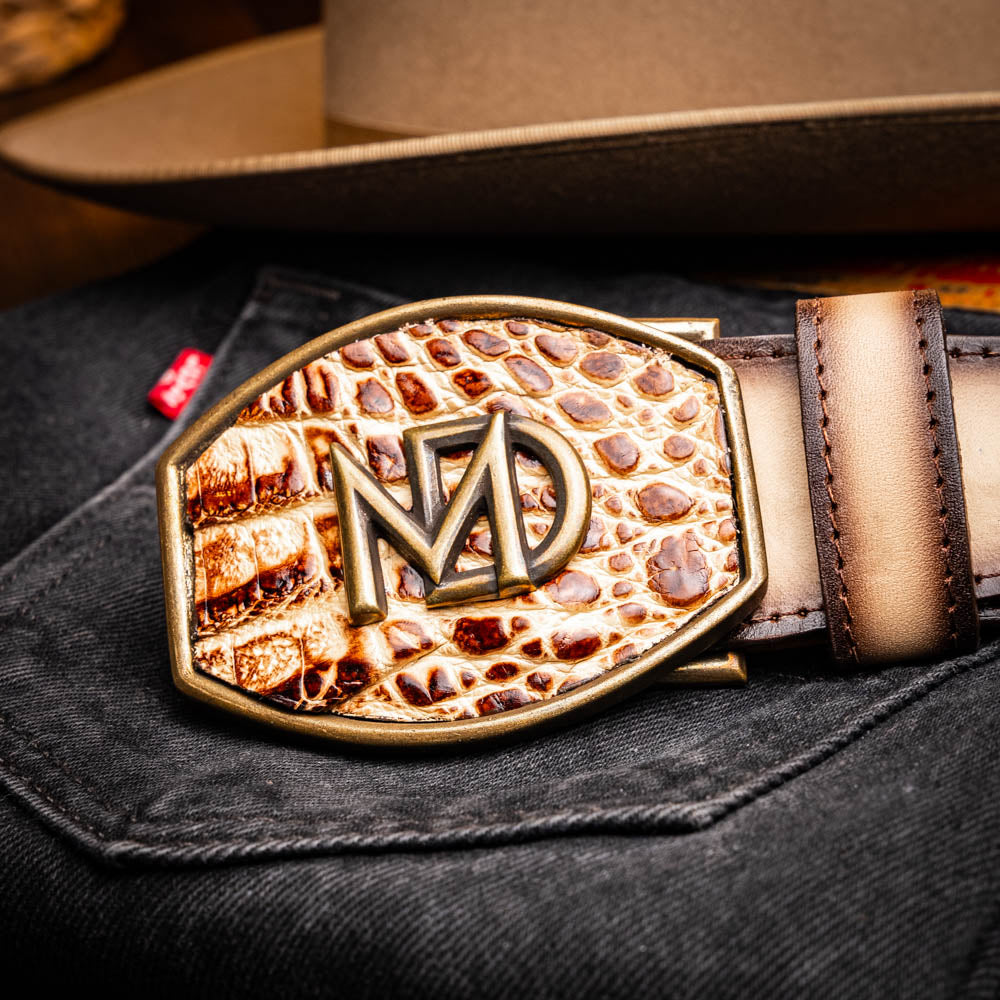 The Texas Belt Stone Orix by Marco Di Milano features embossed tan and brown caiman crocodile leather with a large gold and brown MD logo buckle, shown rolled up against a white background.
