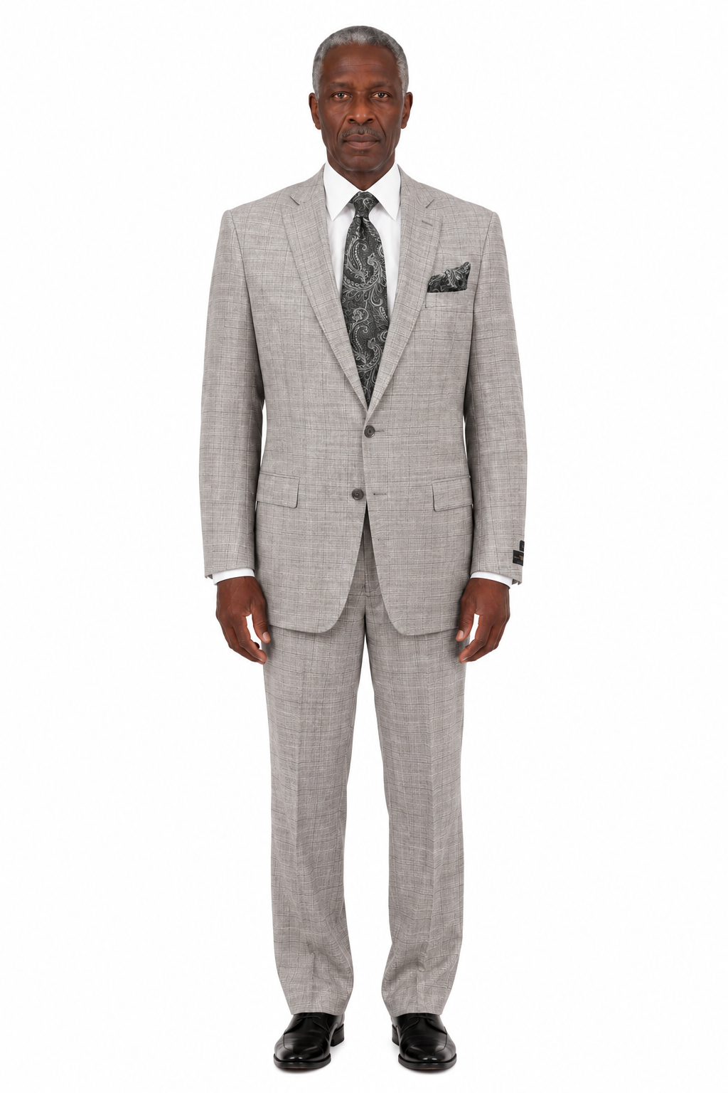 A mannequin dressed in the Tiglio Luxe Dolcetto Modern Fit Wool Suit TL7041—a light gray plaid pure wool suit—paired with a white shirt, paisley-patterned tie, and matching pocket square, is displayed in-store among expertly tailored men’s clothing by Tiglio Luxe.