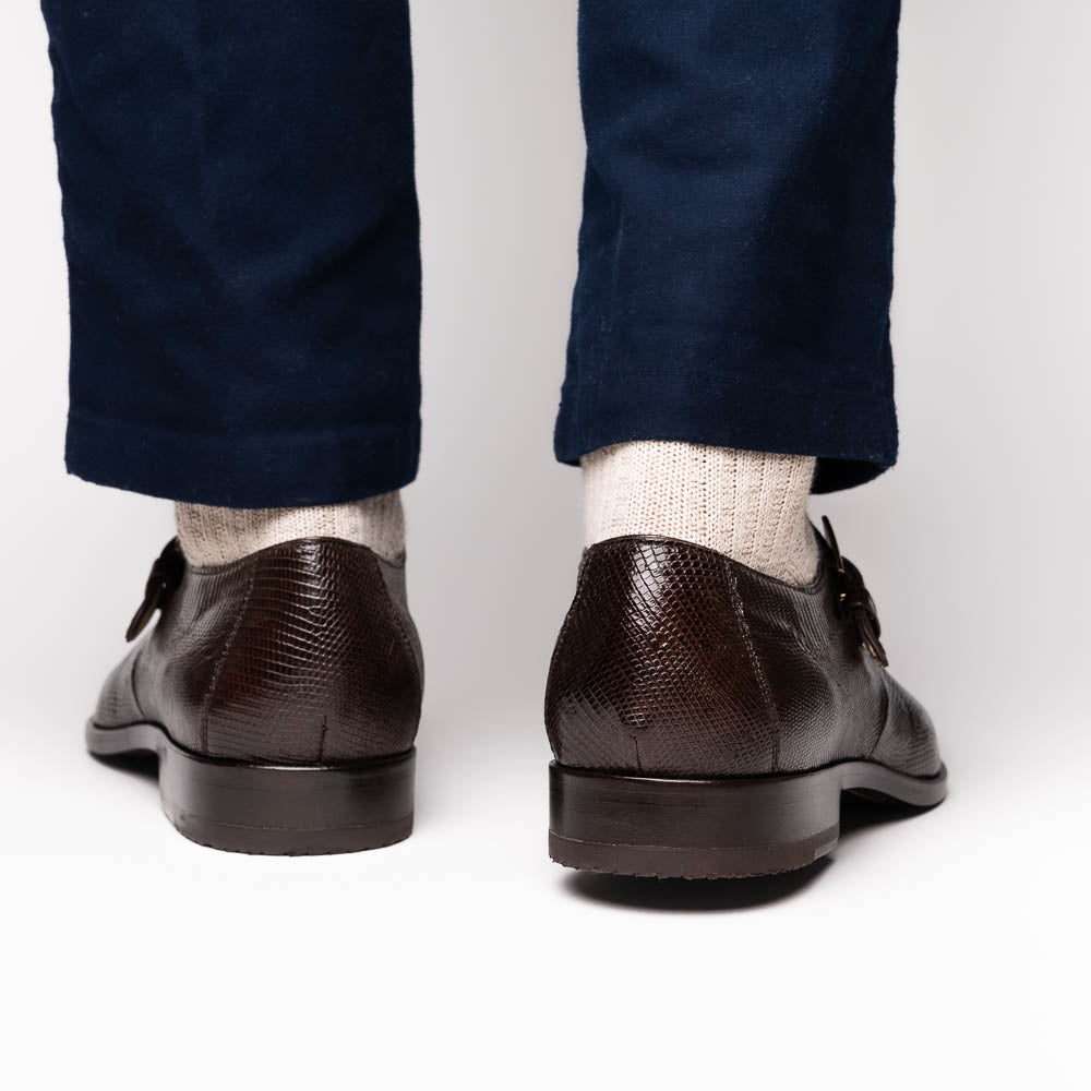 Toluca Brown by Marco Di Milano: luxury men's monk strap shoes in brown crocodile-patterned leather with a side buckle. One shoe stands upright; the other lies on its side to display the sole.