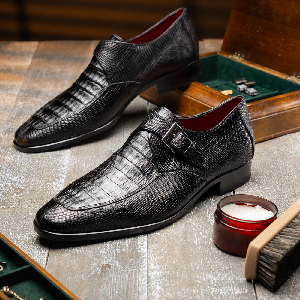 Toluca Black by Marco Di Milano: a black leather dress shoe featuring a crocodile texture and an elegant monk strap side buckle, displayed with one shoe upright and the other revealing its brown leather sole—a refined luxury footwear choice.