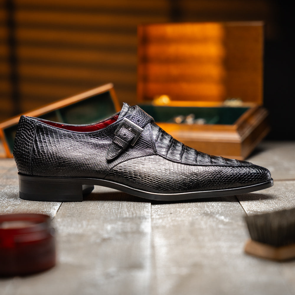 Toluca Black by Marco Di Milano: a black leather dress shoe featuring a crocodile texture and an elegant monk strap side buckle, displayed with one shoe upright and the other revealing its brown leather sole—a refined luxury footwear choice.