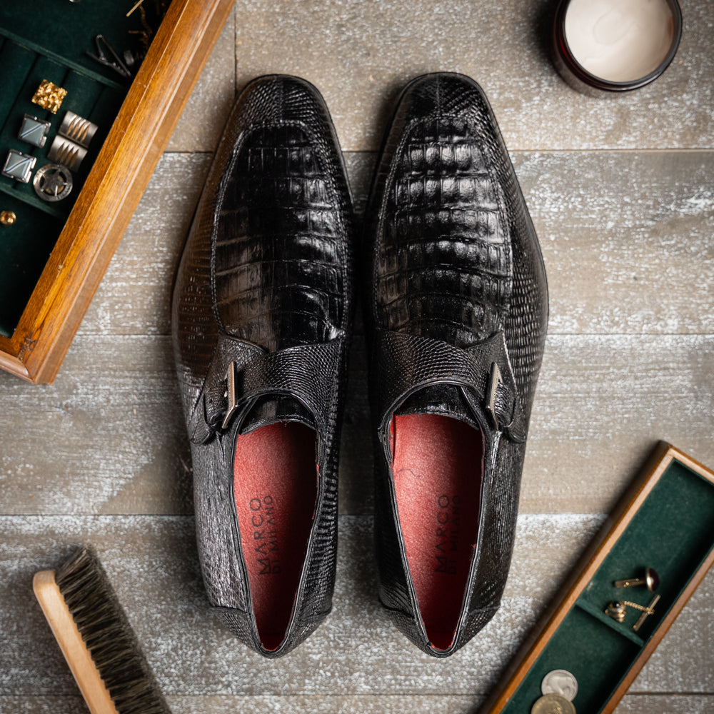 Toluca Black by Marco Di Milano: a black leather dress shoe featuring a crocodile texture and an elegant monk strap side buckle, displayed with one shoe upright and the other revealing its brown leather sole—a refined luxury footwear choice.