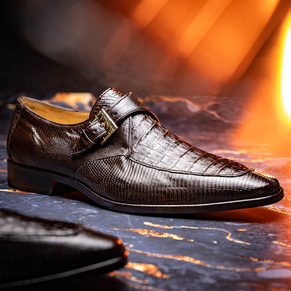Toluca Brown by Marco Di Milano: luxury men's monk strap shoes in brown crocodile-patterned leather with a side buckle. One shoe stands upright; the other lies on its side to display the sole.