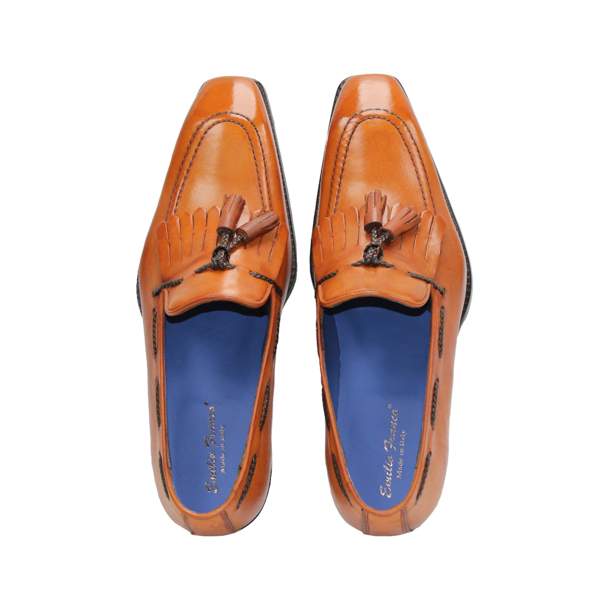 The Emilio Franco Tommaso Gold is a tan leather loafer with a tailored fit, low black heel, tassel detail on the upper, and dark side stitching, shown in side profile against a white background.