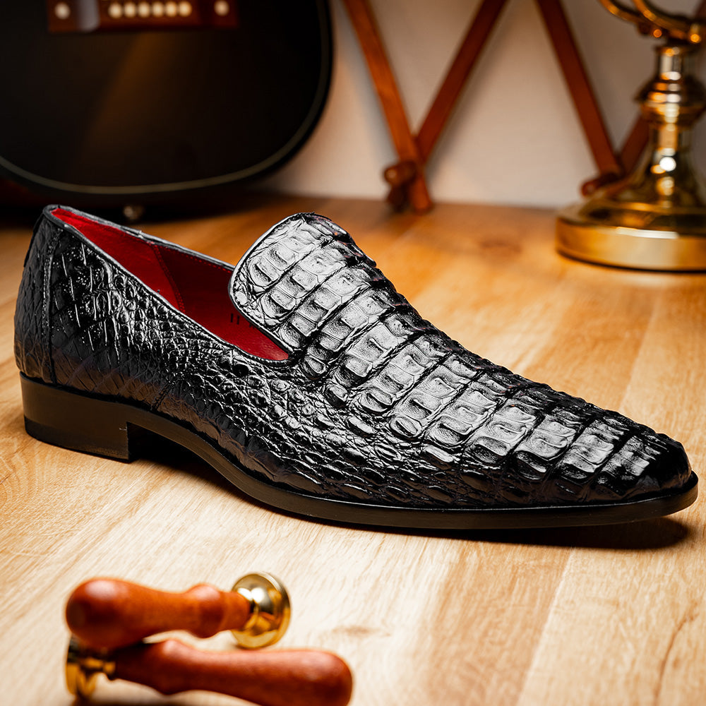 A pair of Marco Di Milano Trento Black loafers crafted from genuine caiman crocodile-pattern leather, showcasing a striking black exterior, red interior lining, and brown soles—one positioned upright and the other on its side. These luxury shoes feature exquisite hand-painted finishes for a truly sophisticated touch.
