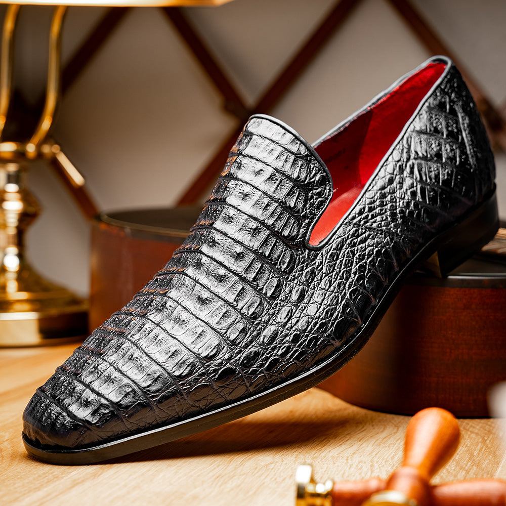 A pair of Marco Di Milano Trento Black loafers crafted from genuine caiman crocodile-pattern leather, showcasing a striking black exterior, red interior lining, and brown soles—one positioned upright and the other on its side. These luxury shoes feature exquisite hand-painted finishes for a truly sophisticated touch.