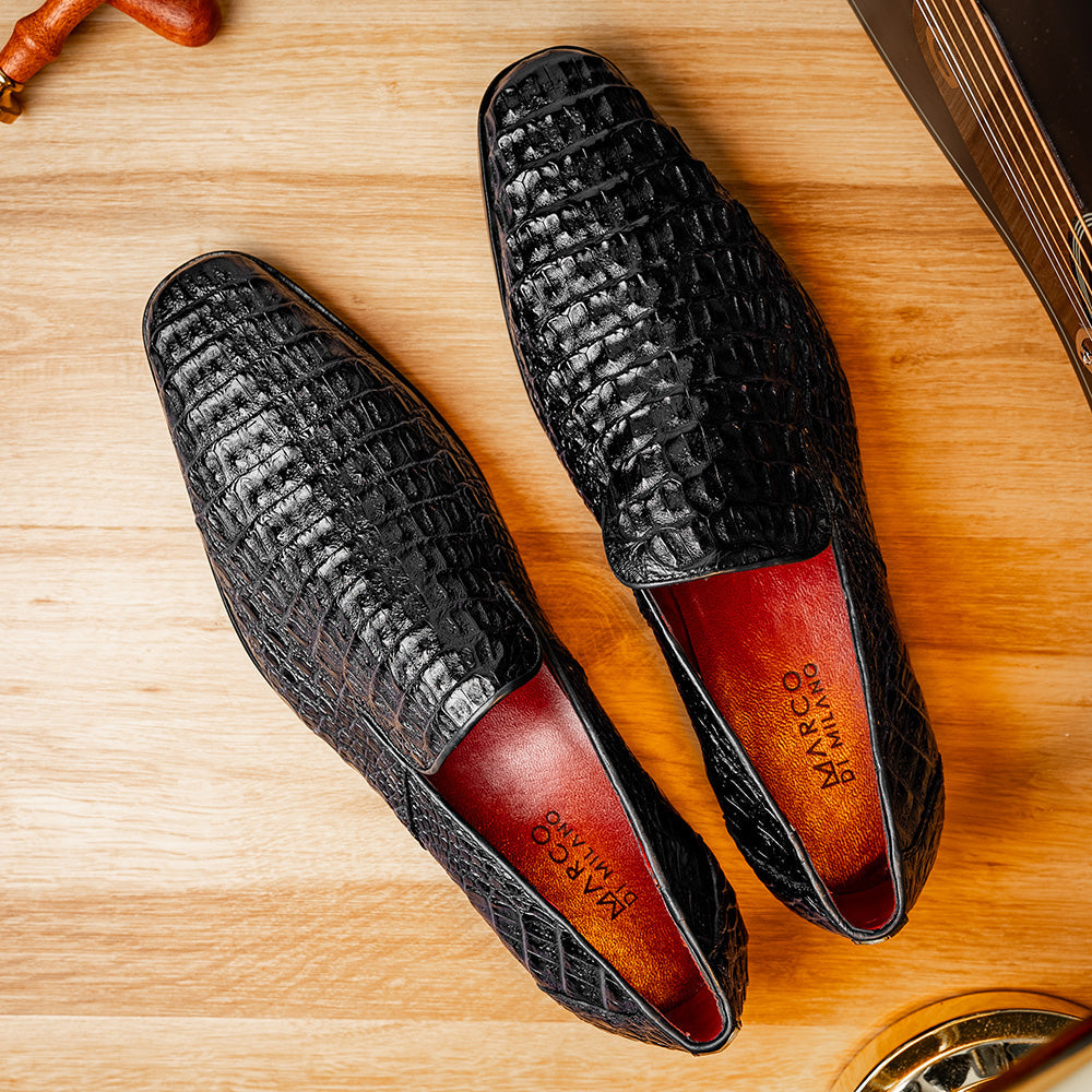 A pair of Marco Di Milano Trento Black loafers crafted from genuine caiman crocodile-pattern leather, showcasing a striking black exterior, red interior lining, and brown soles—one positioned upright and the other on its side. These luxury shoes feature exquisite hand-painted finishes for a truly sophisticated touch.
