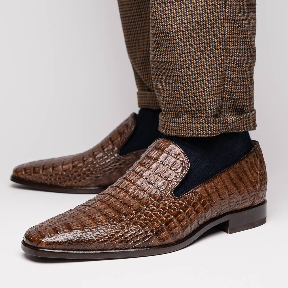 The Marco Di Milano Trento Brown shoes, crafted from genuine caiman crocodile leather, are shown with one upright and one on its side to reveal the sole, highlighting their hand-painted luxury finish.