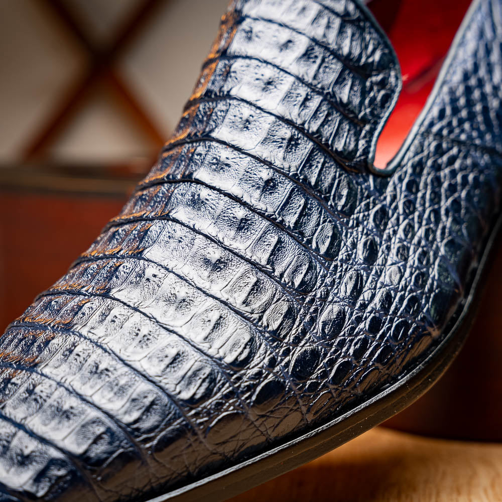 The Trento Navy by Marco Di Milano are dark blue genuine caiman leather loafers featuring hand-painted finishes, red lining, and "Marco Di Milano" branding on the sole.