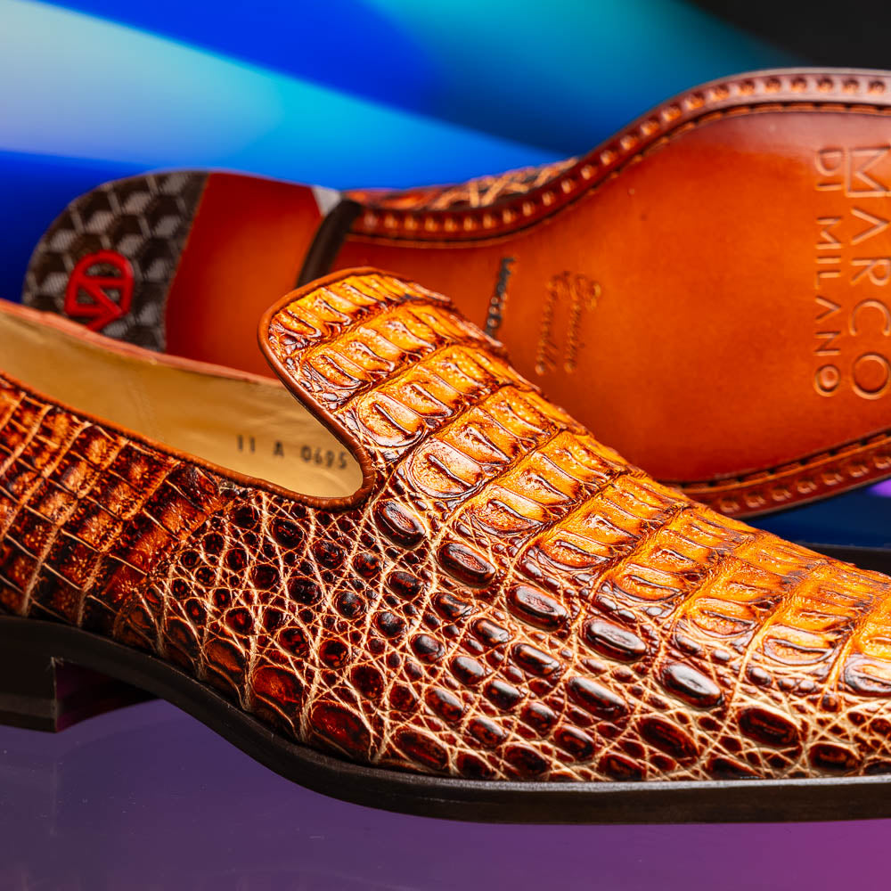 The Marco Di Milano Trento Rustic Cognac shoes, crafted from genuine caiman crocodile leather with a hand-painted finish, are displayed—one upright and one showing the sole—to highlight this luxurious footwear’s exquisite design.