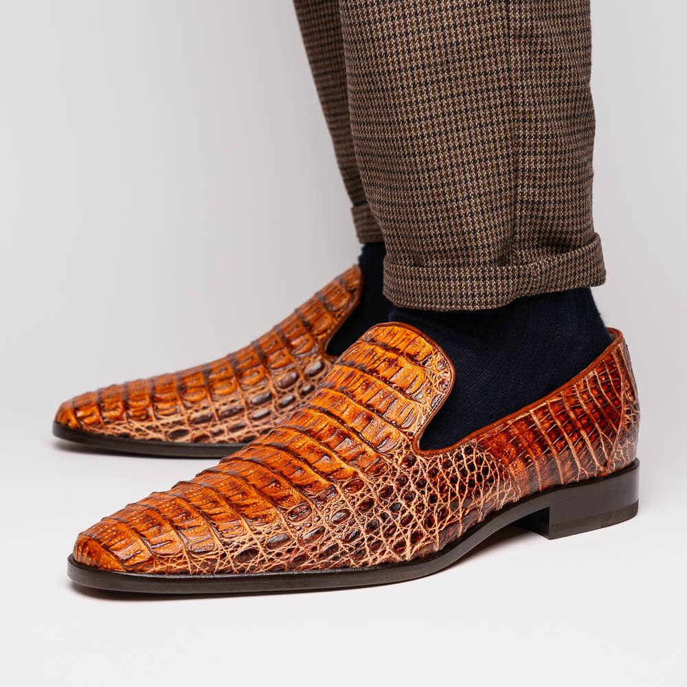 The Marco Di Milano Trento Rustic Cognac shoes, crafted from genuine caiman crocodile leather with a hand-painted finish, are displayed—one upright and one showing the sole—to highlight this luxurious footwear’s exquisite design.