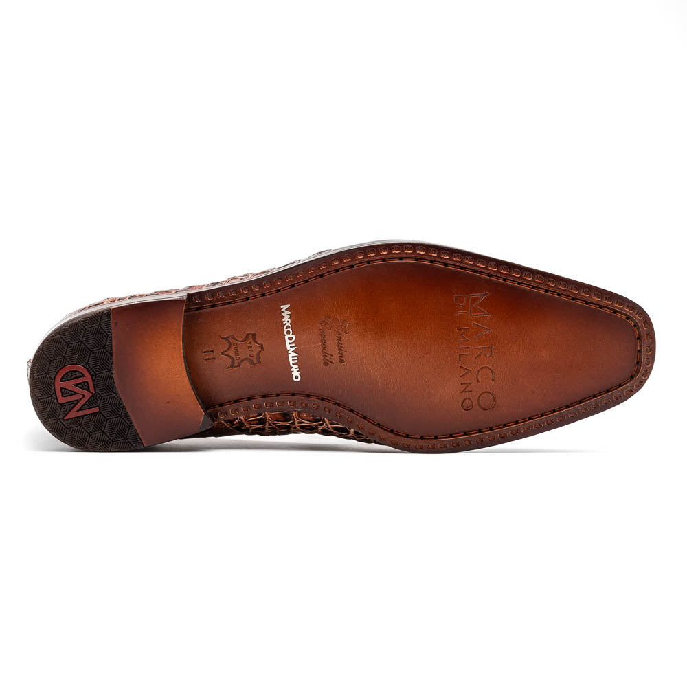 The Marco Di Milano Trento Rustic Cognac shoes, crafted from genuine caiman crocodile leather with a hand-painted finish, are displayed—one upright and one showing the sole—to highlight this luxurious footwear’s exquisite design.