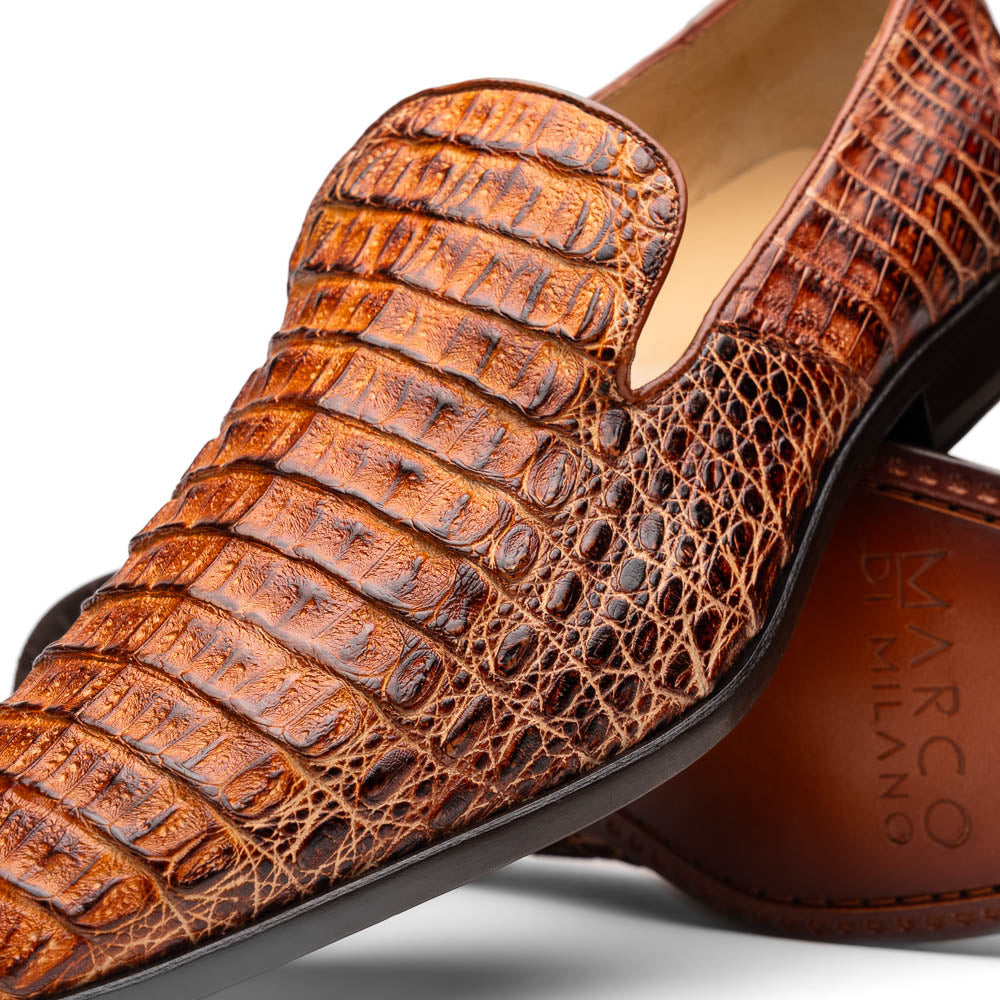 The Marco Di Milano Trento Rustic Cognac shoes, crafted from genuine caiman crocodile leather with a hand-painted finish, are displayed—one upright and one showing the sole—to highlight this luxurious footwear’s exquisite design.