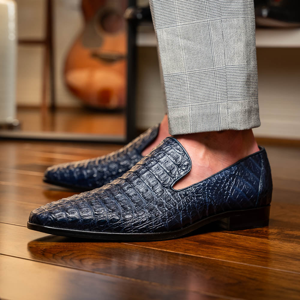 The Trento Navy by Marco Di Milano are dark blue genuine caiman leather loafers featuring hand-painted finishes, red lining, and "Marco Di Milano" branding on the sole.