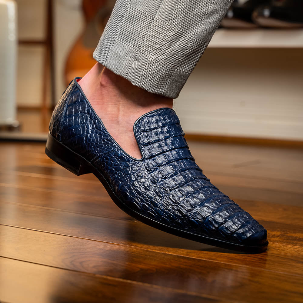 The Trento Navy by Marco Di Milano are dark blue genuine caiman leather loafers featuring hand-painted finishes, red lining, and "Marco Di Milano" branding on the sole.