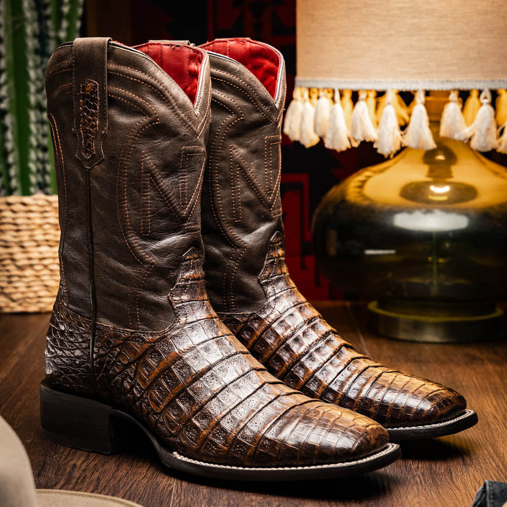 A pair of Marco Di Milano Tucson Aged Brown cowboy boots with textured caiman belly leather—one boot stands upright while the other displays its sole, branded "Marco di Milano.