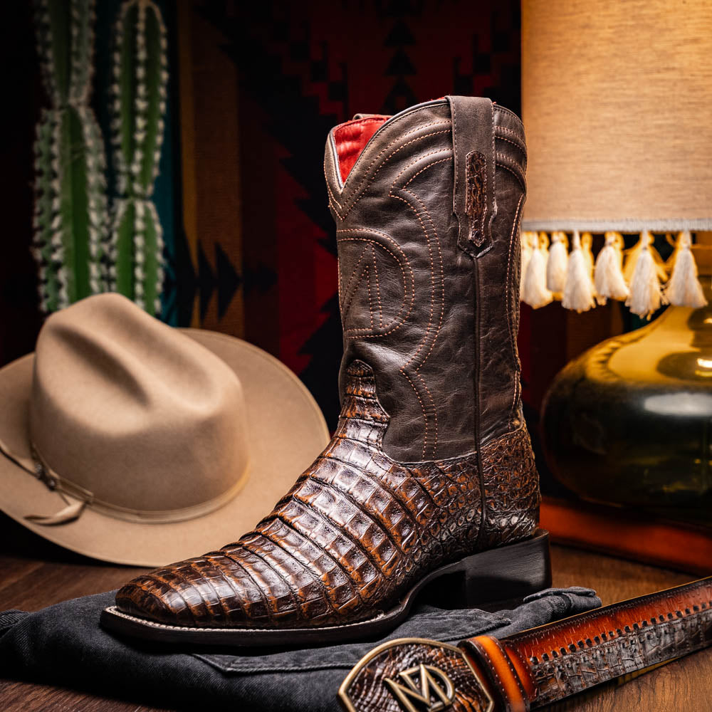 A pair of Marco Di Milano Tucson Aged Brown cowboy boots with textured caiman belly leather—one boot stands upright while the other displays its sole, branded "Marco di Milano.