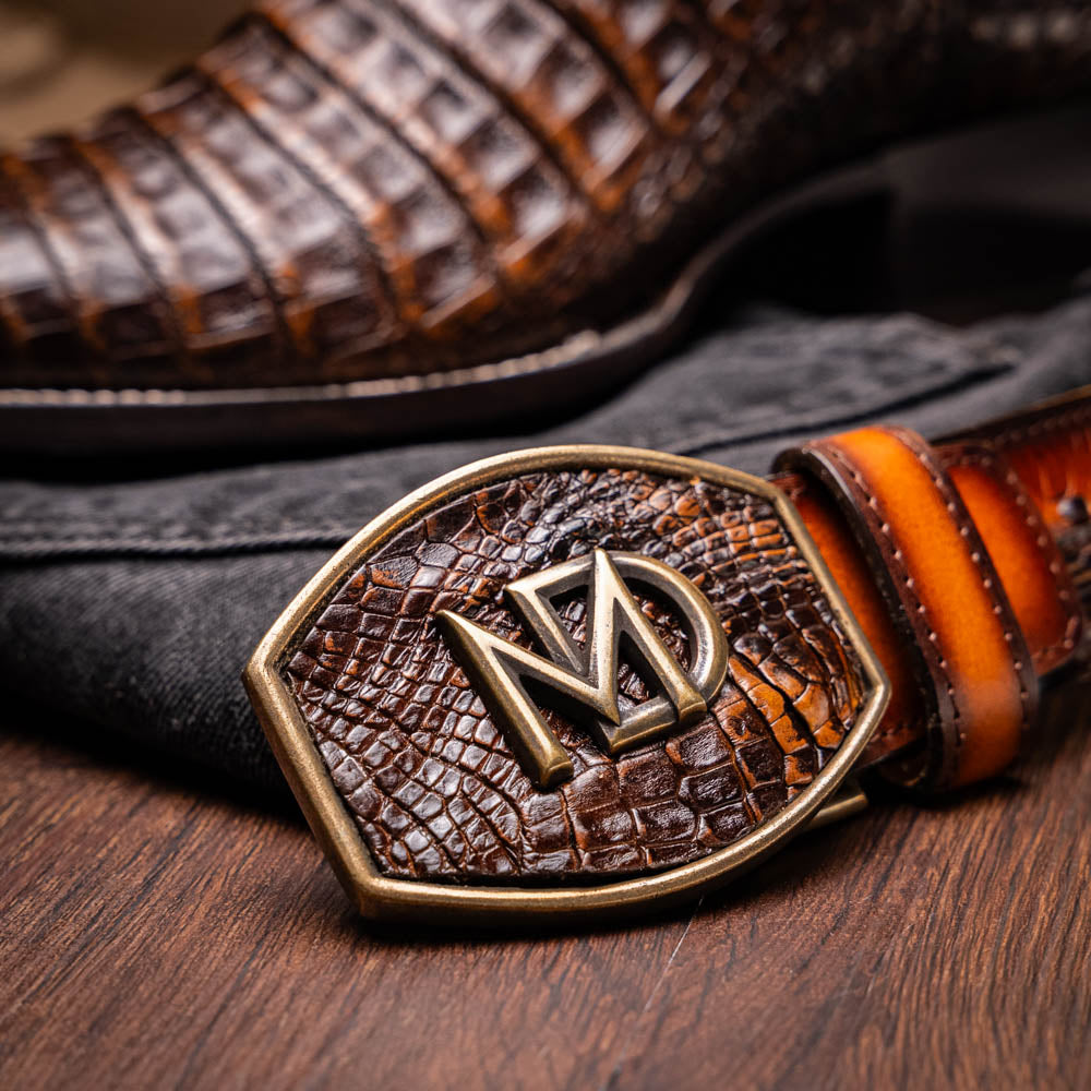A pair of Marco Di Milano Tucson Aged Brown cowboy boots with textured caiman belly leather—one boot stands upright while the other displays its sole, branded "Marco di Milano.