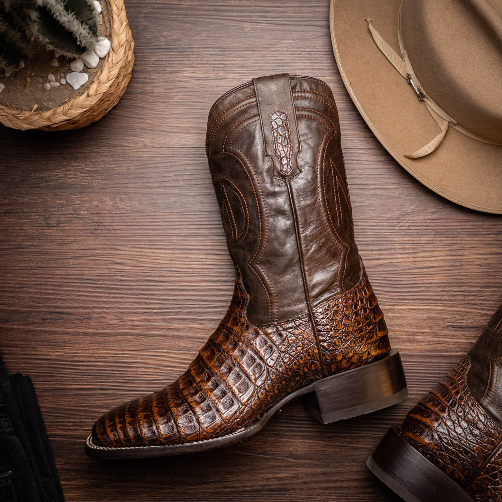 A pair of Marco Di Milano Tucson Aged Brown cowboy boots with textured caiman belly leather—one boot stands upright while the other displays its sole, branded "Marco di Milano.