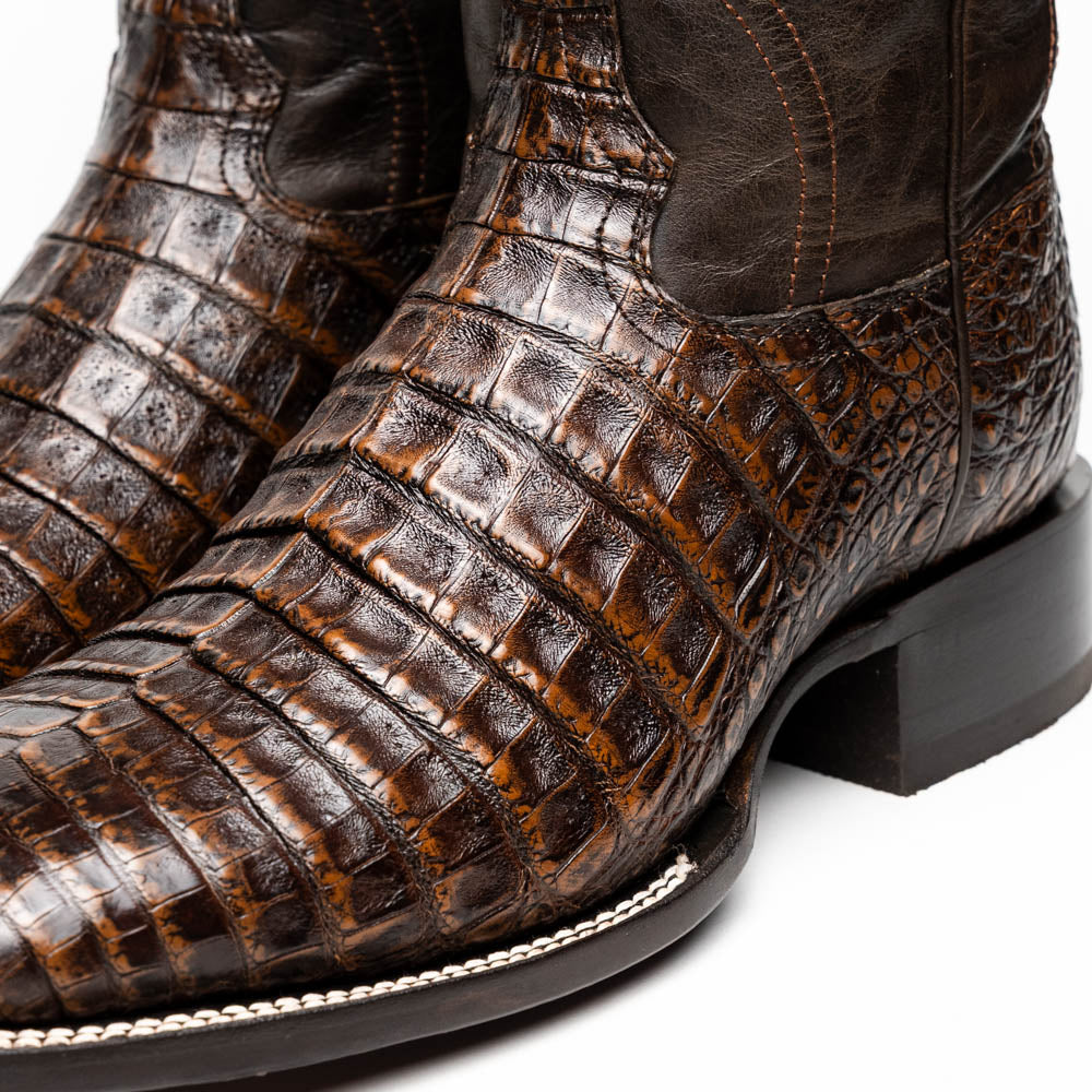 A pair of Marco Di Milano Tucson Aged Brown cowboy boots with textured caiman belly leather—one boot stands upright while the other displays its sole, branded "Marco di Milano.
