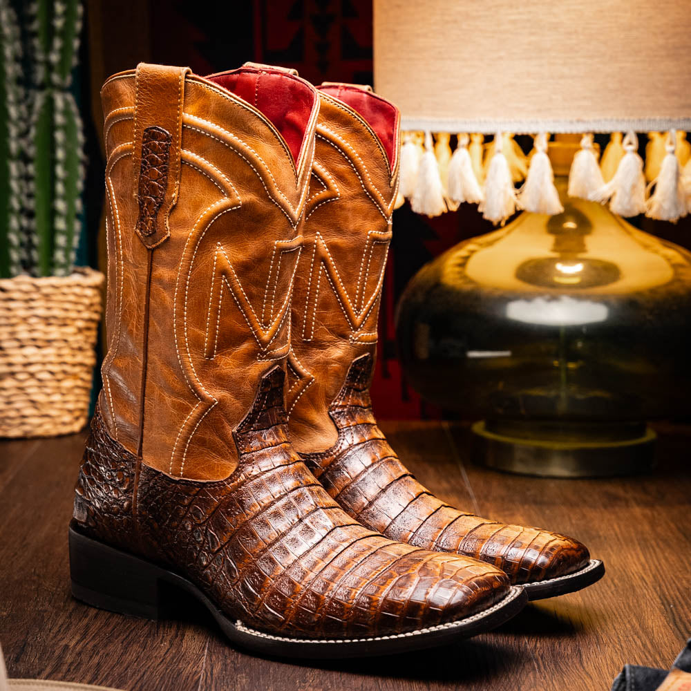 A pair of Tucson Aged Maple brown genuine leather western boots by Marco Di Milano with a textured finish; one boot upright, the other displaying the sole with "Marco Di Milano" branding.