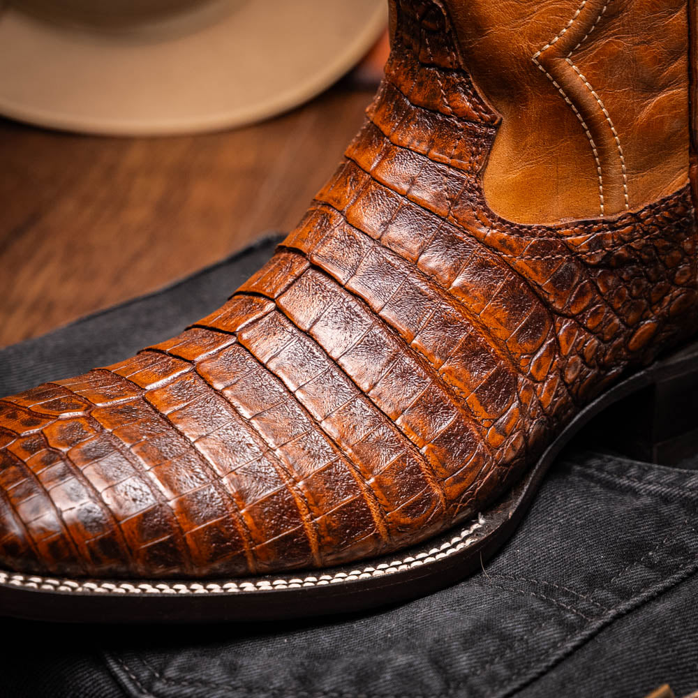 A pair of Tucson Aged Maple brown genuine leather western boots by Marco Di Milano with a textured finish; one boot upright, the other displaying the sole with "Marco Di Milano" branding.