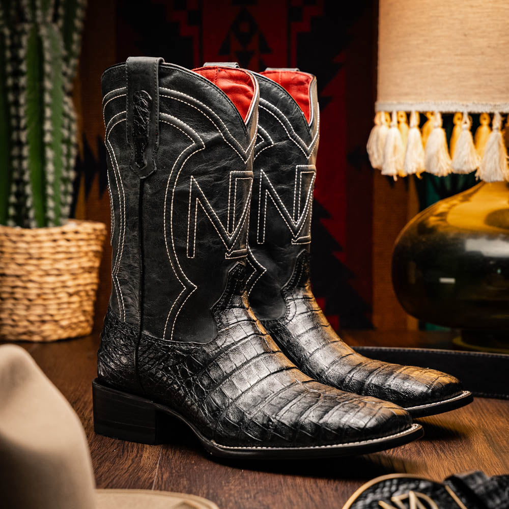 A pair of Tucson Black cowboy boots by Marco Di Milano; one boot stands upright highlighting the decorative stitching, while the other lies on its side showing the branded sole.