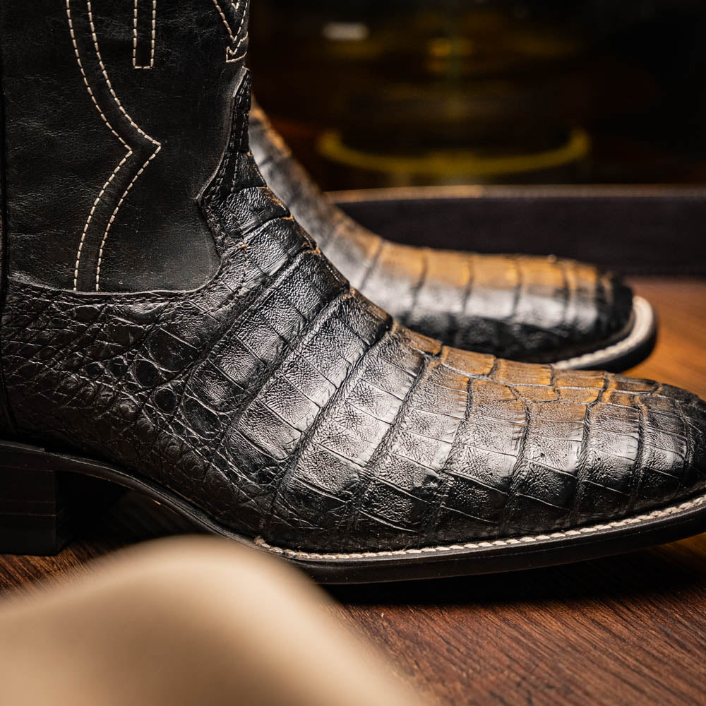 A pair of Tucson Black cowboy boots by Marco Di Milano; one boot stands upright highlighting the decorative stitching, while the other lies on its side showing the branded sole.