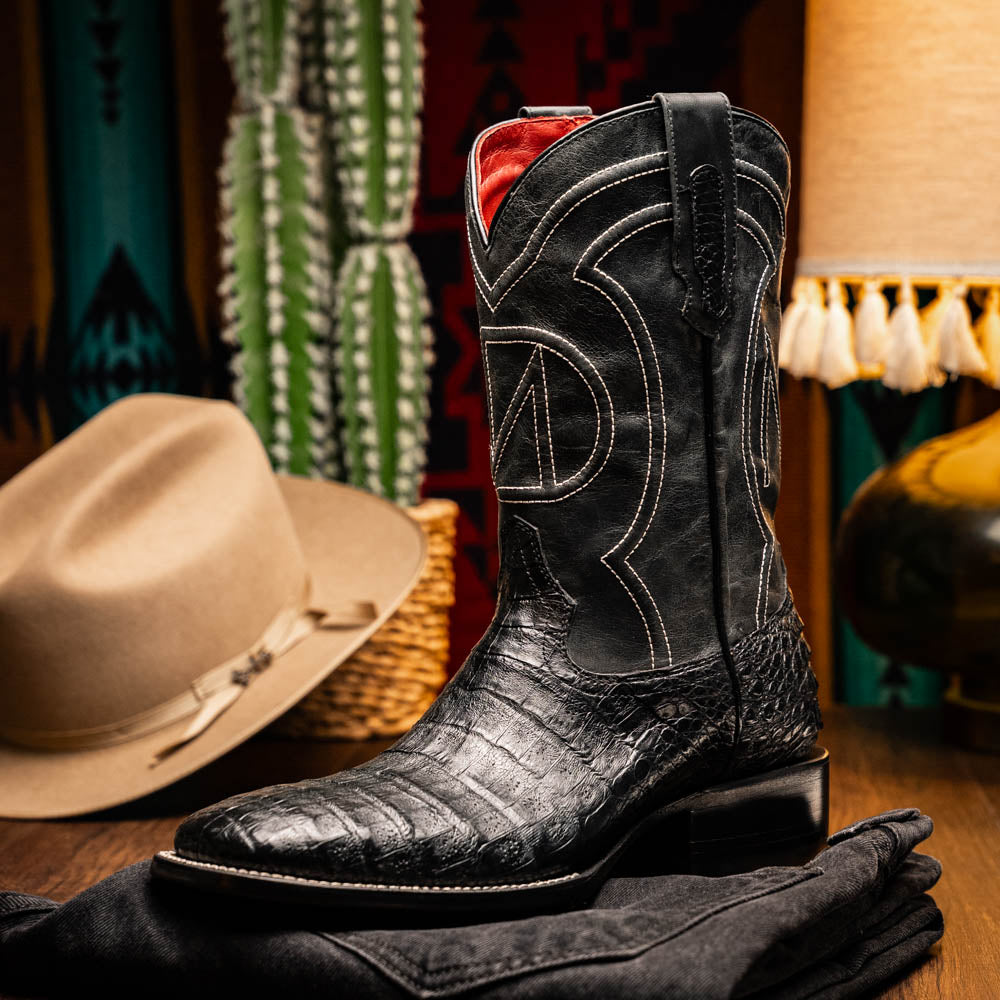 A pair of Tucson Black cowboy boots by Marco Di Milano; one boot stands upright highlighting the decorative stitching, while the other lies on its side showing the branded sole.