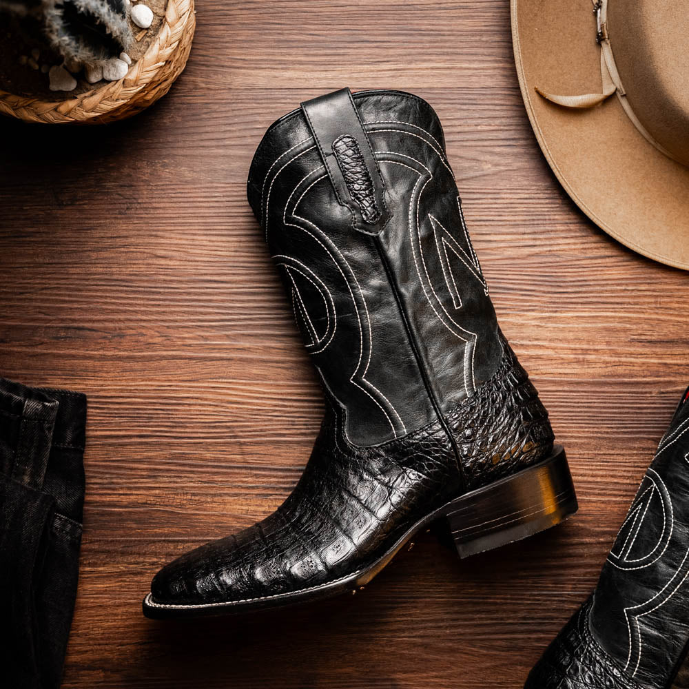 A pair of Tucson Black cowboy boots by Marco Di Milano; one boot stands upright highlighting the decorative stitching, while the other lies on its side showing the branded sole.